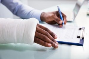 A truck driver with an injured right arm signing a truck accident claim form in Seattle.